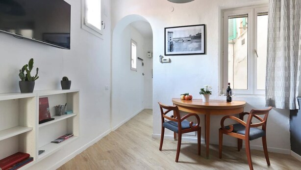 A dining area with a round wooden table, two chairs, a potted plant, and a framed picture on the wall. - Florence Central Market (Firenze)