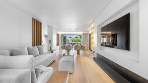 Ein modernes Wohnzimmer mit einer Couch, einem Hocker und einem Essbereich mit Stühlen und einem Tisch.