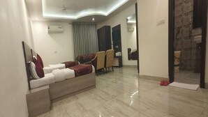 A modern hotel room with a sofa bed, a flat-screen TV, and a large mirror. - Hotel Lakshmi Palace (New Delhi)