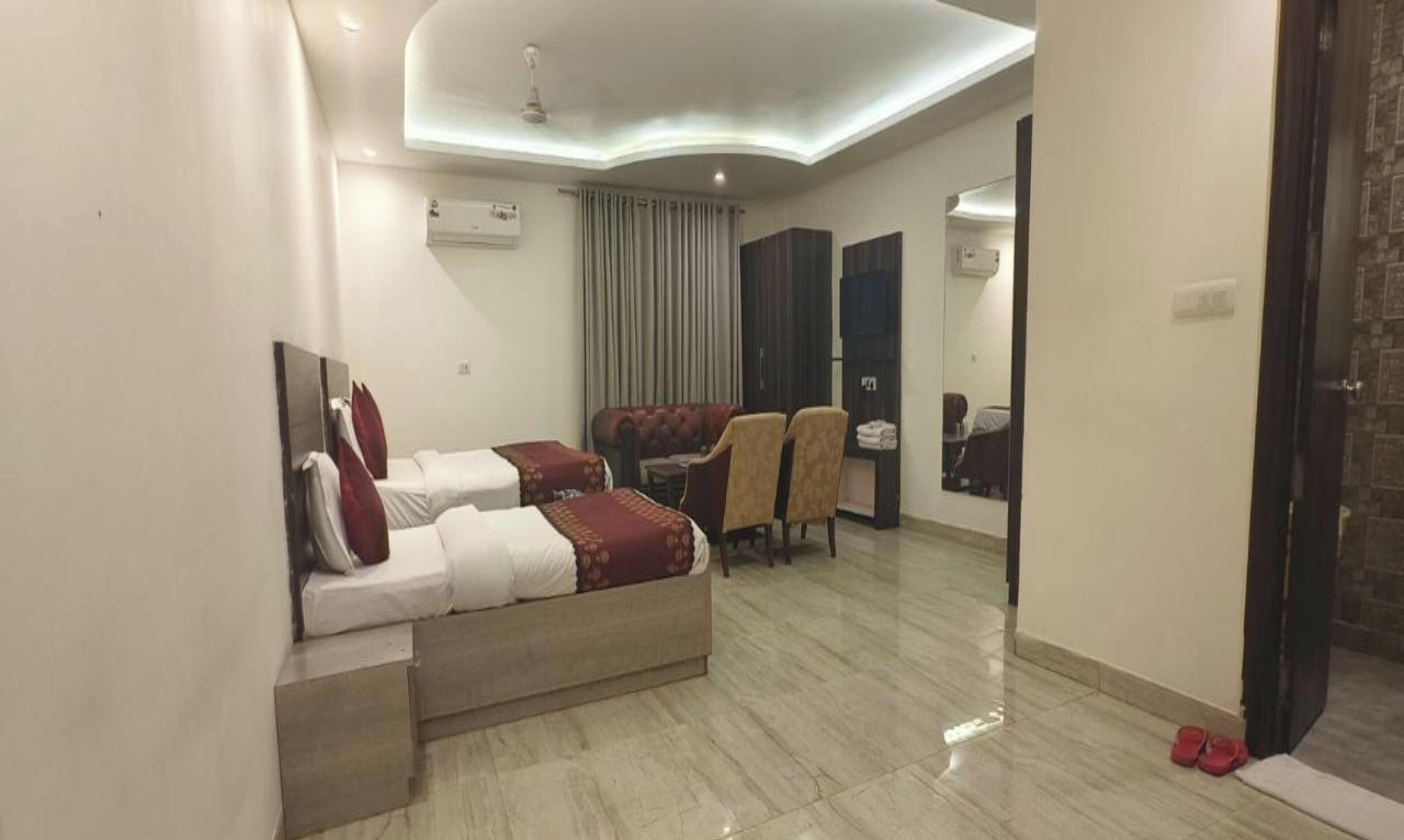A hotel room with two beds, a sofa, a mirror, and a ceiling light.