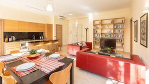 A modern apartment with a dining area, kitchen, living room, and a bookshelf. - Rental in Rome Pateras Garden Apartment (Rome)