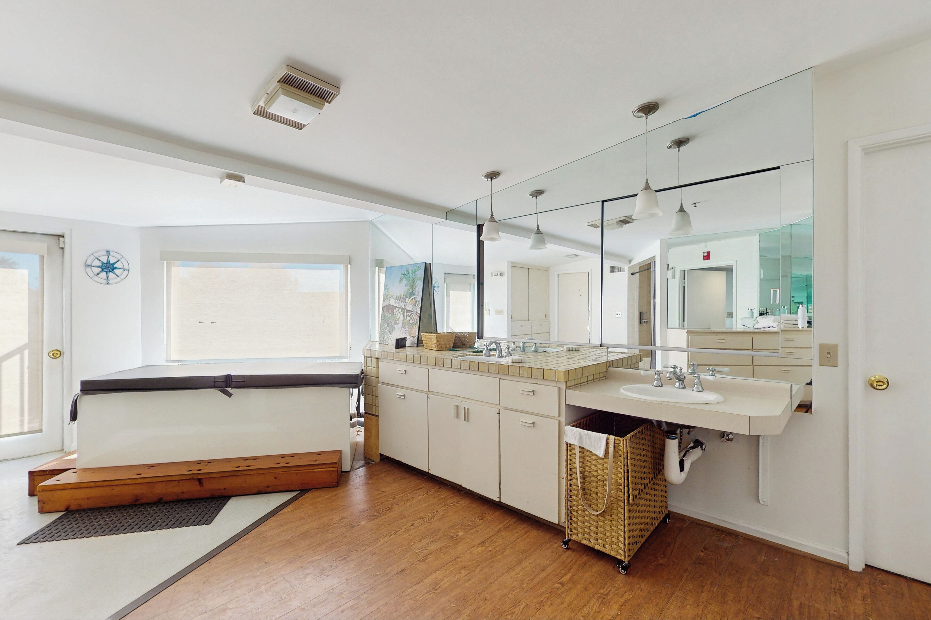 A modern bathroom with a large mirror, two sinks, and a wooden floor.