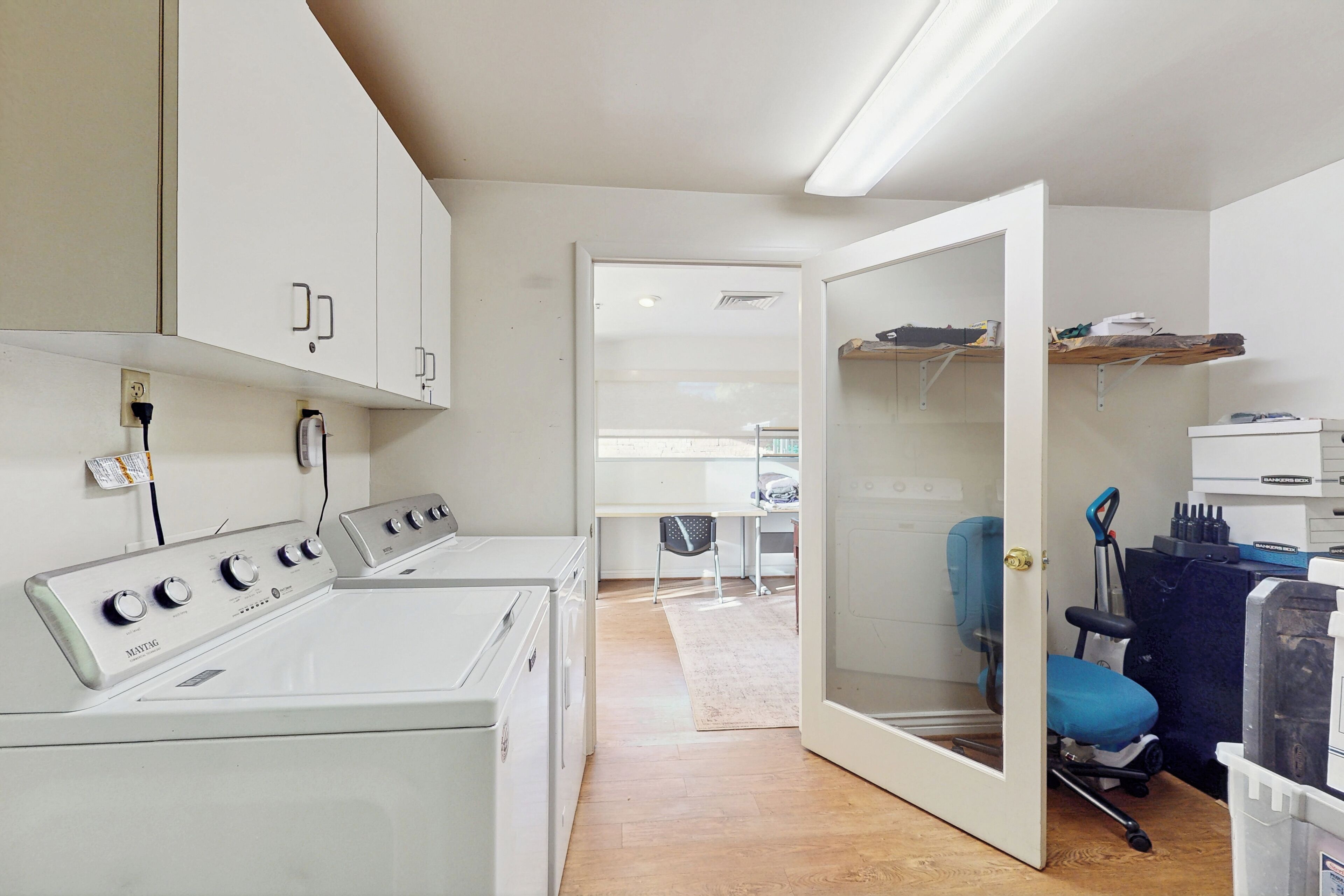 A laundry area with a washing machine, a dryer, and a small desk with a chair.