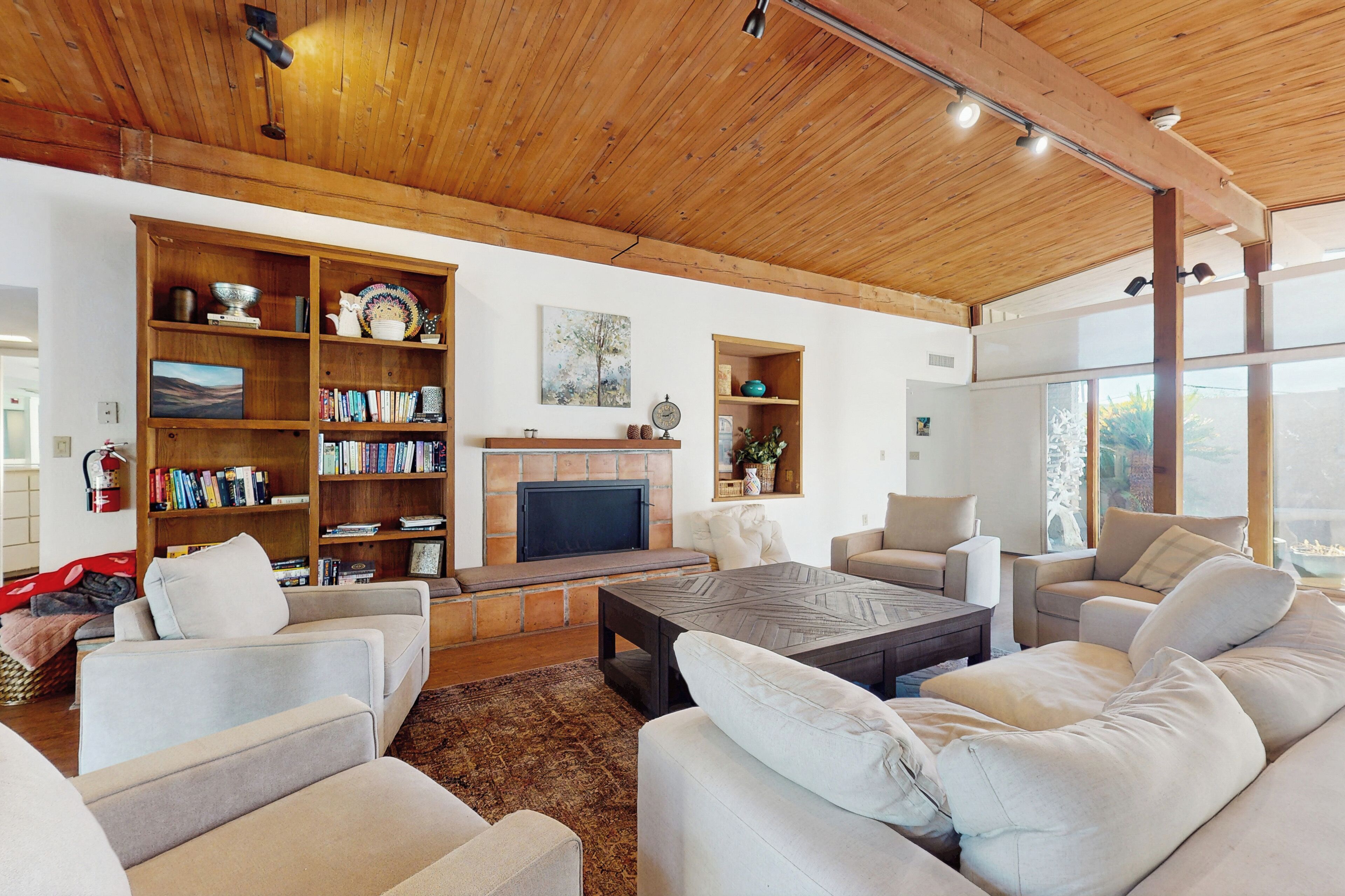 A spacious living room with a fireplace, comfortable seating, and a large bookshelf.