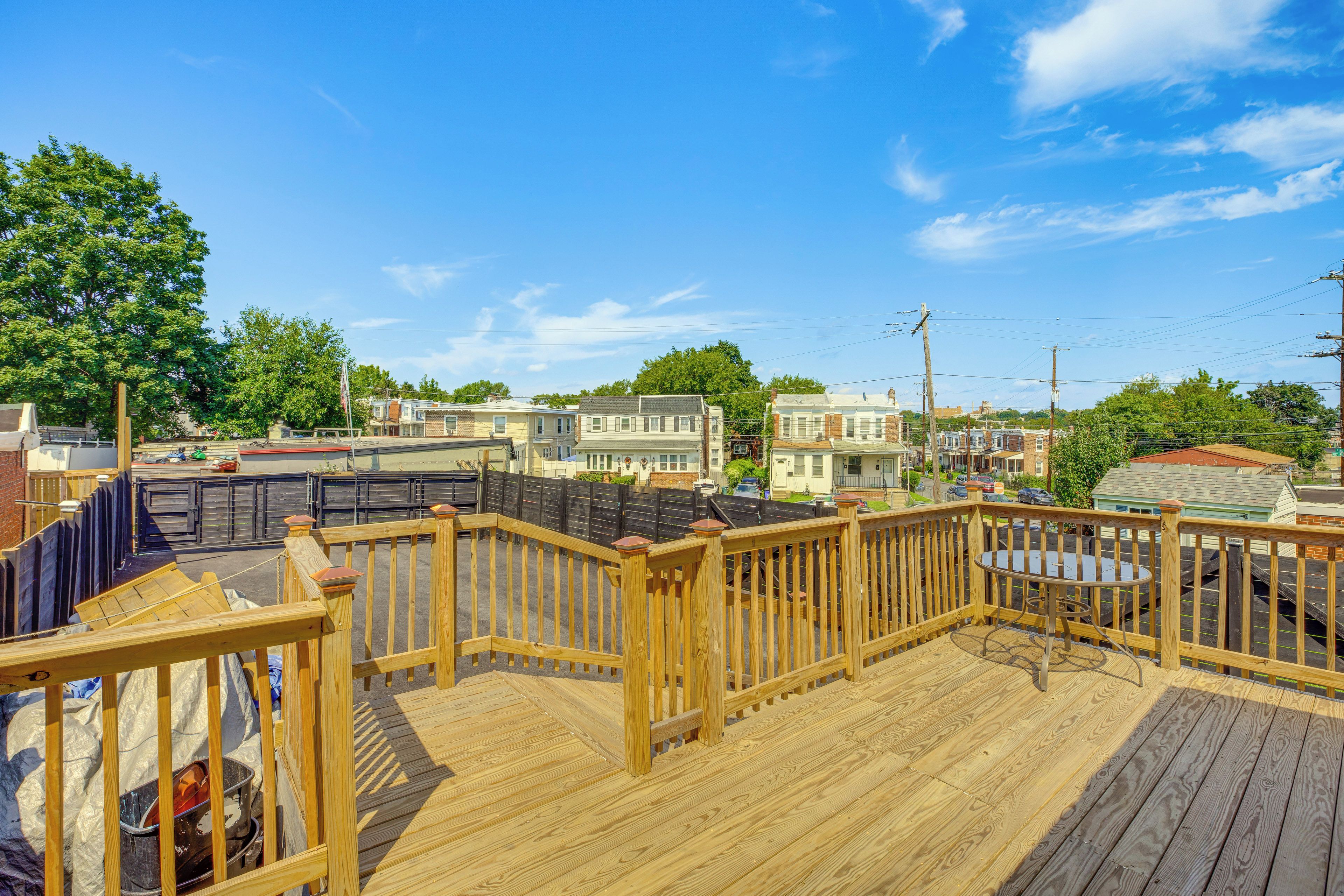 Una terraza de madera con vista a un barrio residencial, con casas y un cielo despejado.