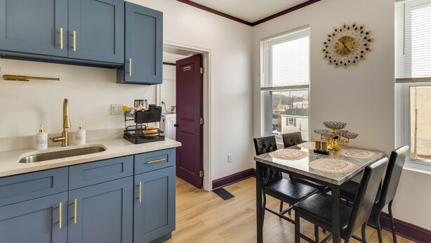 Una cocina moderna con gabinetes azules, un fregadero y un comedor con una mesa y sillas.