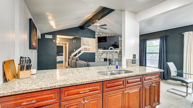 A kitchen with granite countertops, wooden cabinets, a built-in stove, and a ceiling fan. - Near Six Flags & Seaworld: San Antonio Family Home (San Antonio)