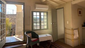 Een kamer met een rieten stoel, een tafeltje, een raam en een deur.