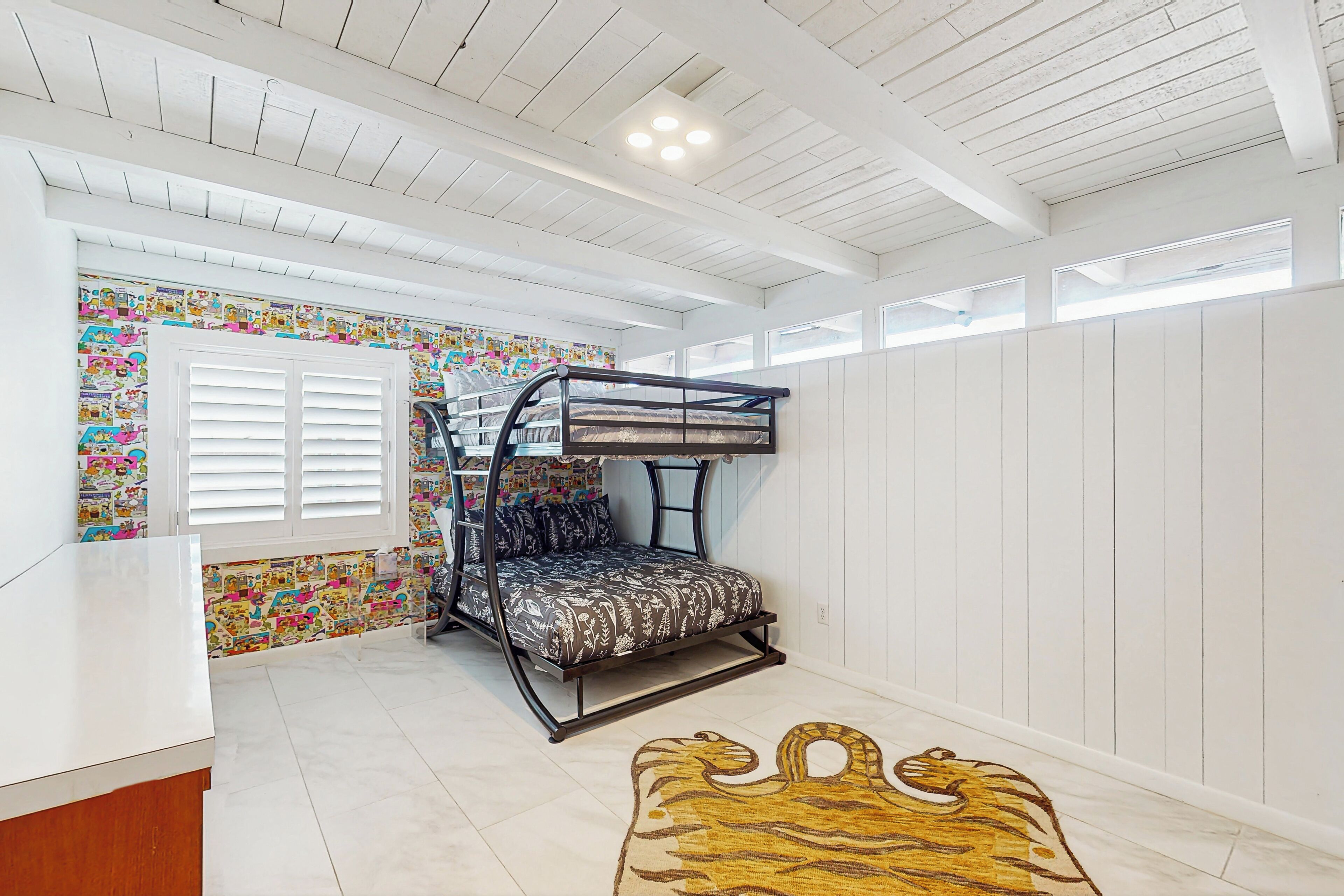 Een slaapkamer met een stapelbed, een kleurrijke muur, een wit plafond en een houten vloer.