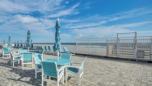 A beachside deck with lounge chairs and striped umbrellas, overlooking the ocean. - Steps to Ocean: Daytona Beach Condo w/ Patio! (Daytona Beach)