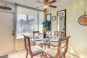 A dining area with a glass table, wooden chairs, a ceiling fan, and a welcome sign. - Steps to Ocean: Daytona Beach Condo w/ Patio! (Daytona Beach)