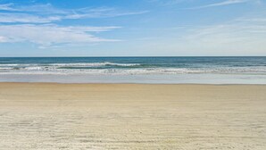 Een strand met een heldere lucht en een rustige zee.
