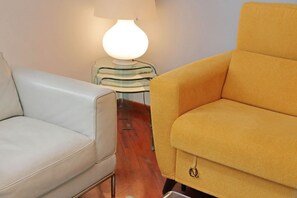 A room with a light-colored sofa, a mustard-colored armchair, and a modern lamp on a glass table. - UNA FINESTRA SULLA CUPOLA DI SAN PIETRO (Roma)
