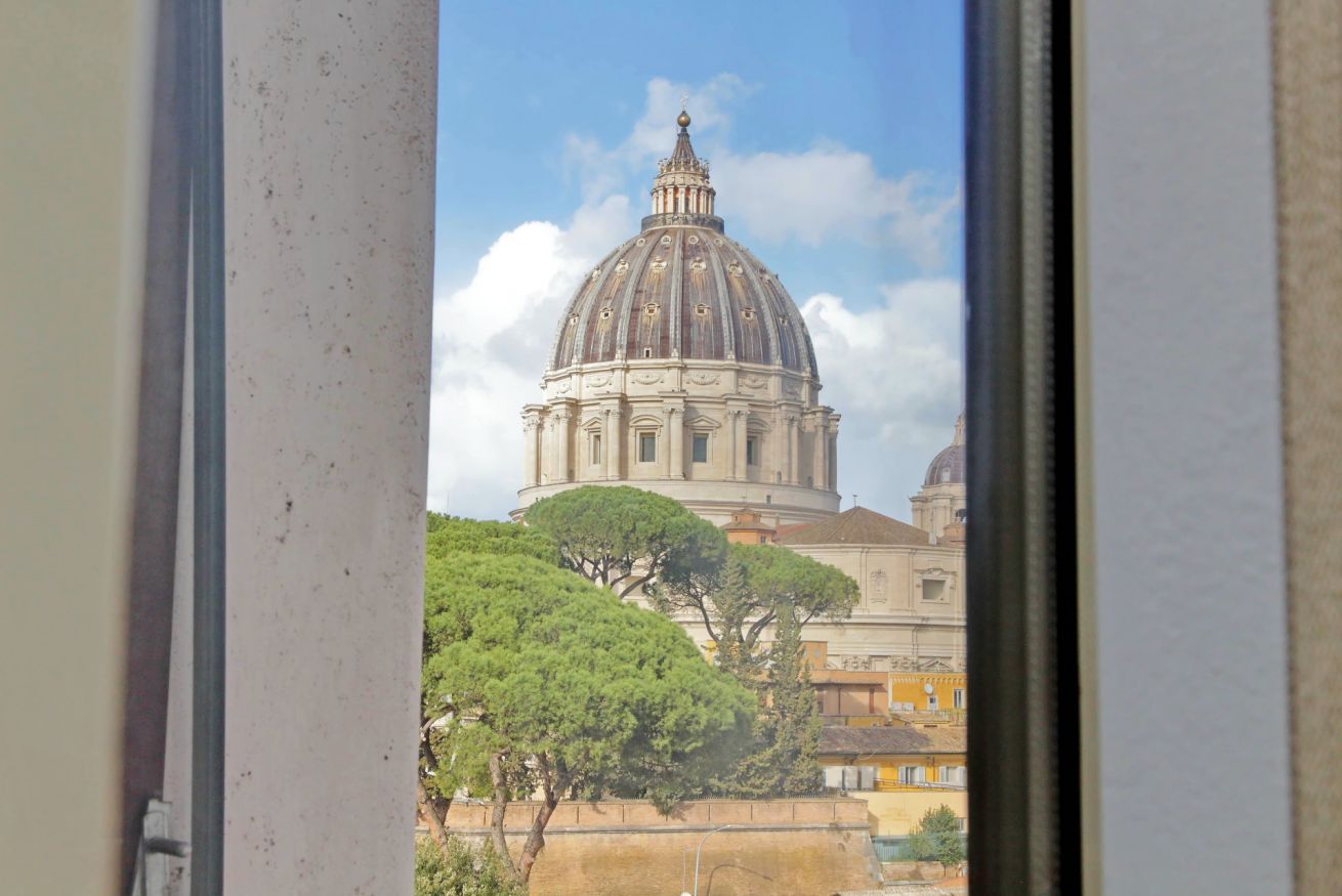 A view of a large, historic building with a dome, surrounded by trees and other buildings.