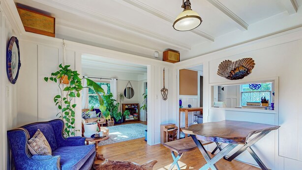 A spacious living room with a blue sofa, a wooden dining table, and a large window. - 3BR Craftsman House w/ Patio, Workspace & WD (Berkeley)