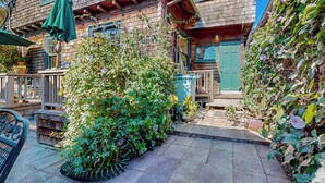 A brick house with a green door, a patio with a table and chairs, and a garden with various plants. - 3BR Craftsman House w/ Patio, Workspace & WD (Berkeley)