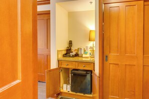 Ein kleines Badezimmer mit Waschtisch aus Holz, einem Spiegel und einem kleinen Kühlschrank.
