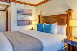 Ein Hotelzimmer mit einem großen Bett, einem hölzernen Kopfteil und drei gerahmten Bildern an der Wand.