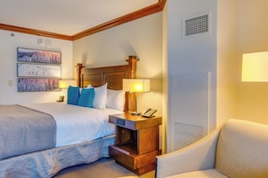 A hotel room with a large bed, a nightstand with a lamp, a chair, and artwork on the wall. - Everline Resort Studio w/ Luxury Resort Perks (Olympic Valley)