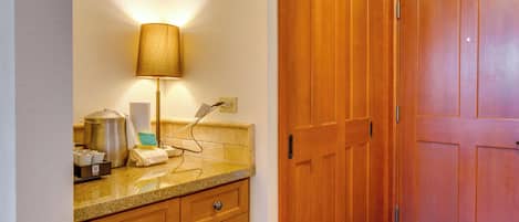 Una cocina con encimeras de granito, armarios de madera, una olla de acero inoxidable y una lámpara.