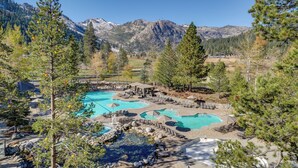 Un resort con diverse piscine, una vasca idromassaggio e montagne sullo sfondo.