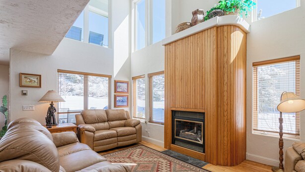A spacious living room with a fireplace, leather sofas, and large windows. - 3BR Townhome w/ Mountain View & Balcony (Driggs)