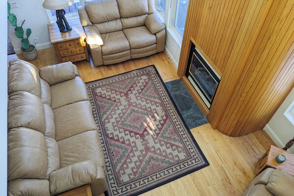 A cozy living room with a beige sectional sofa, a patterned rug, a wooden coffee table, and a fireplace. - 3BR Townhome w/ Mountain View & Balcony (Driggs)