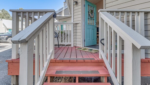 A wooden porch with a red floor and white railings, leading to a turquoise door with a wreath. - Walk to Midtown Ruidoso! Cozy Eagles Nest Condo (Ruidoso)
