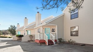 A row of two-story houses with a front porch, a blue door, and a chimney. - Walk to Midtown Ruidoso! Cozy Eagles Nest Condo (Ruidoso)
