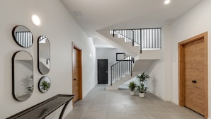 Een modern interieur met een trap, een console tafel en spiegels aan de muur.
