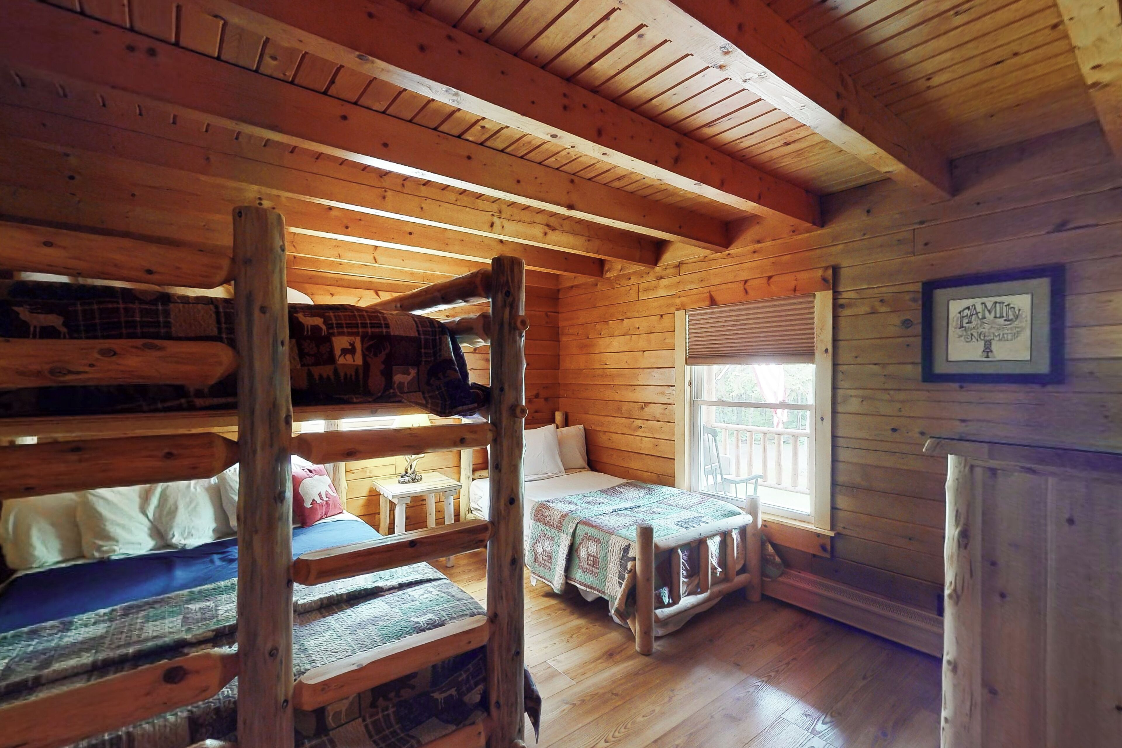 A cabin with a bunk bed, a single bed, and a small table.