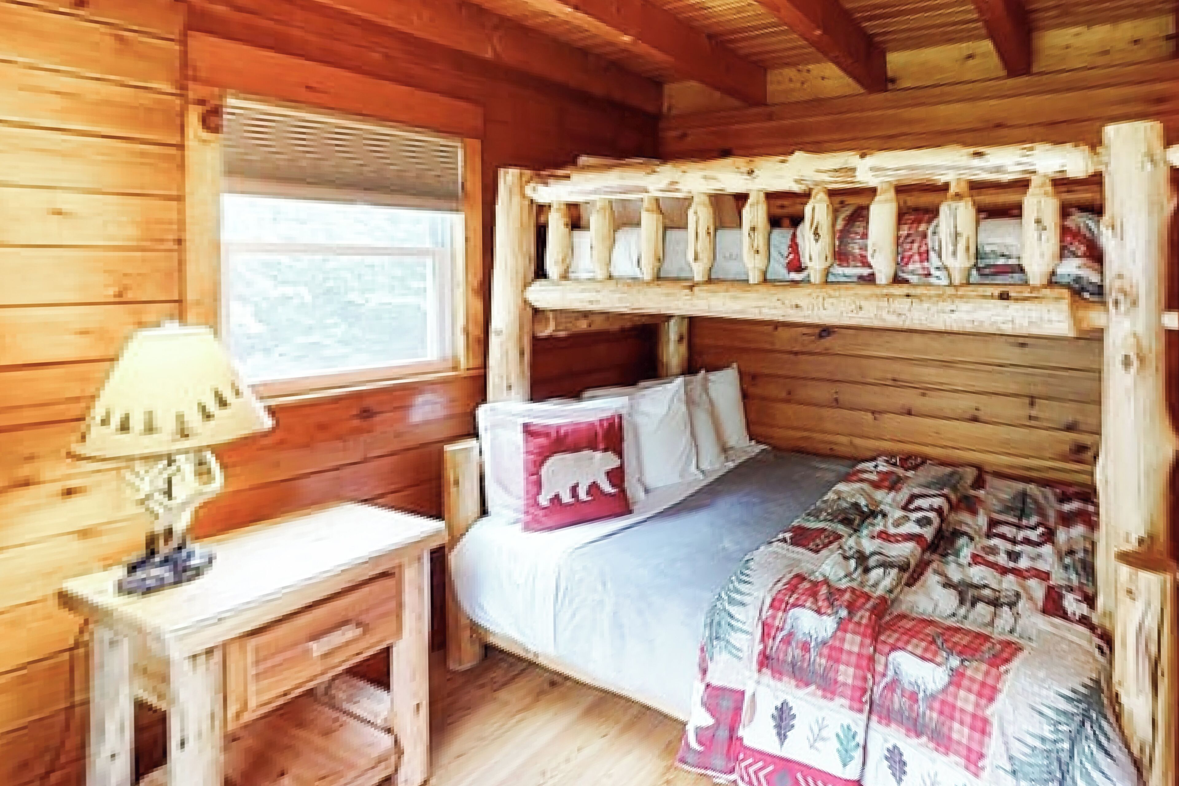 Ein Schlafzimmer einer Holzhütte mit einem Etagenbett, einem Nachttisch mit Lampe und einem Fenster mit Jalousien.