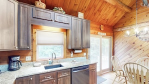 Una cocina con armarios de madera, horno integrado, cafetera y un lavabo.