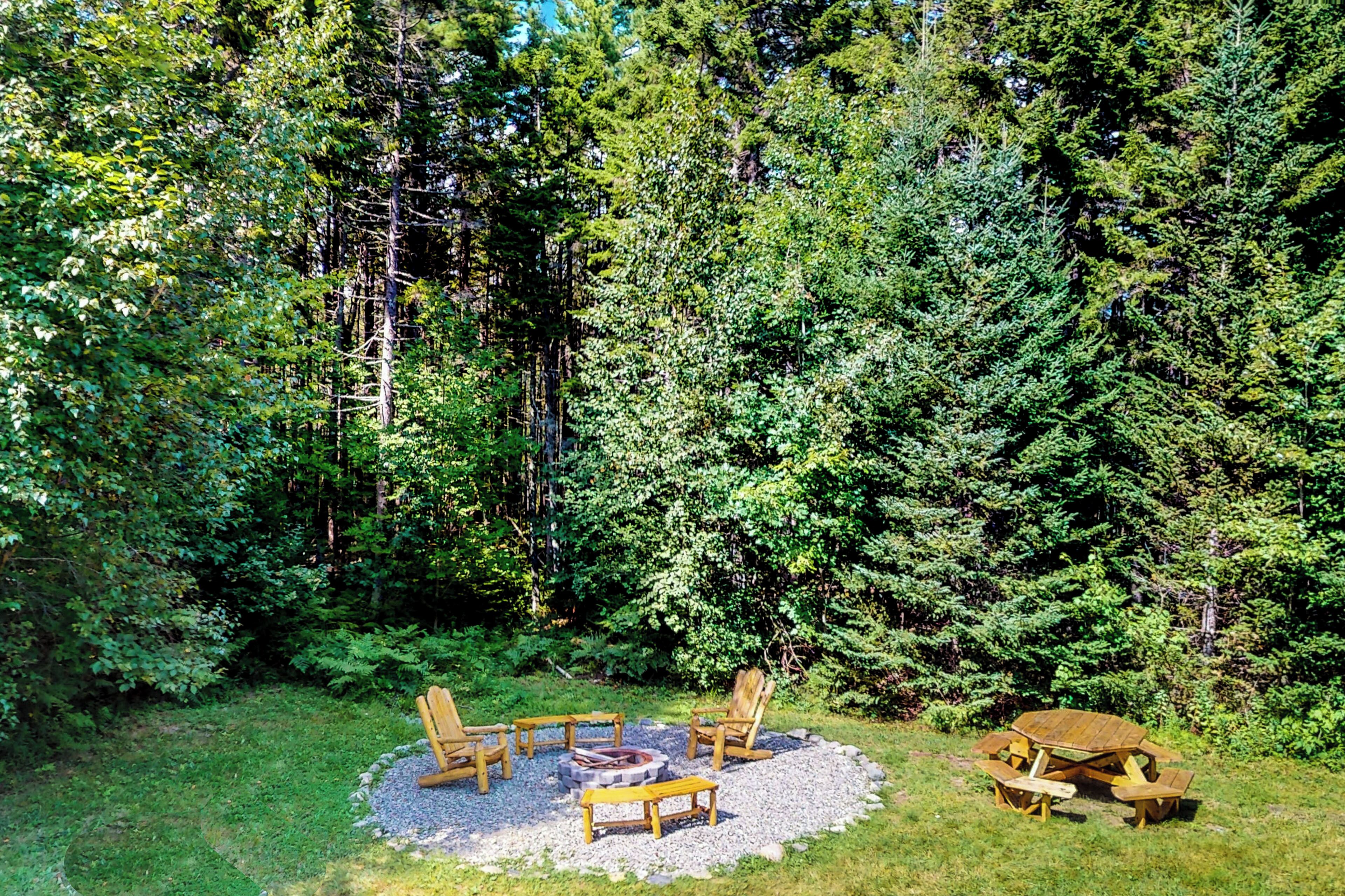 A circular outdoor seating area with a fire pit, surrounded by trees.