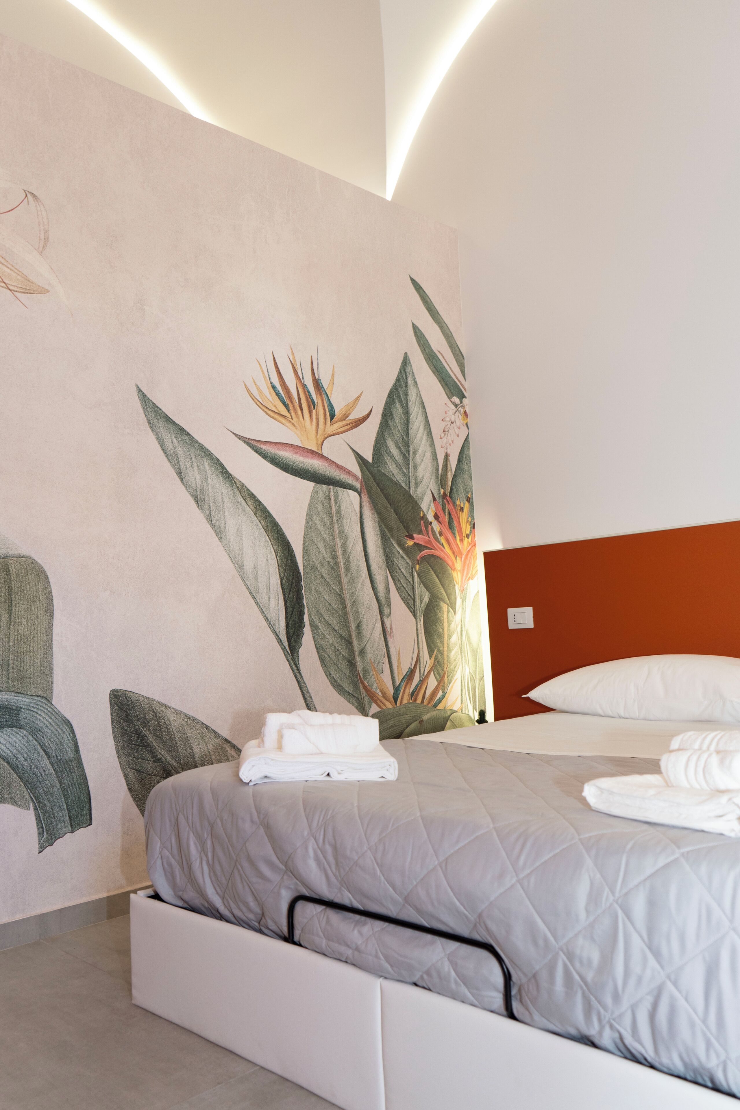 A modern hotel room with a bed, a nightstand, and a wall mural.