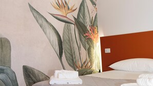 Een moderne hotelkamer met een bed, nachtkastje en een muurschildering.