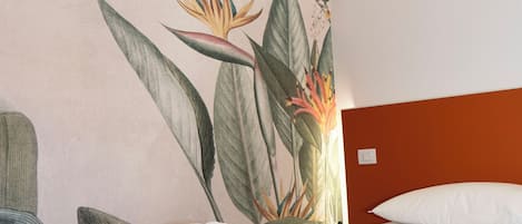 A modern hotel room with a bed, a nightstand, and a wall mural.