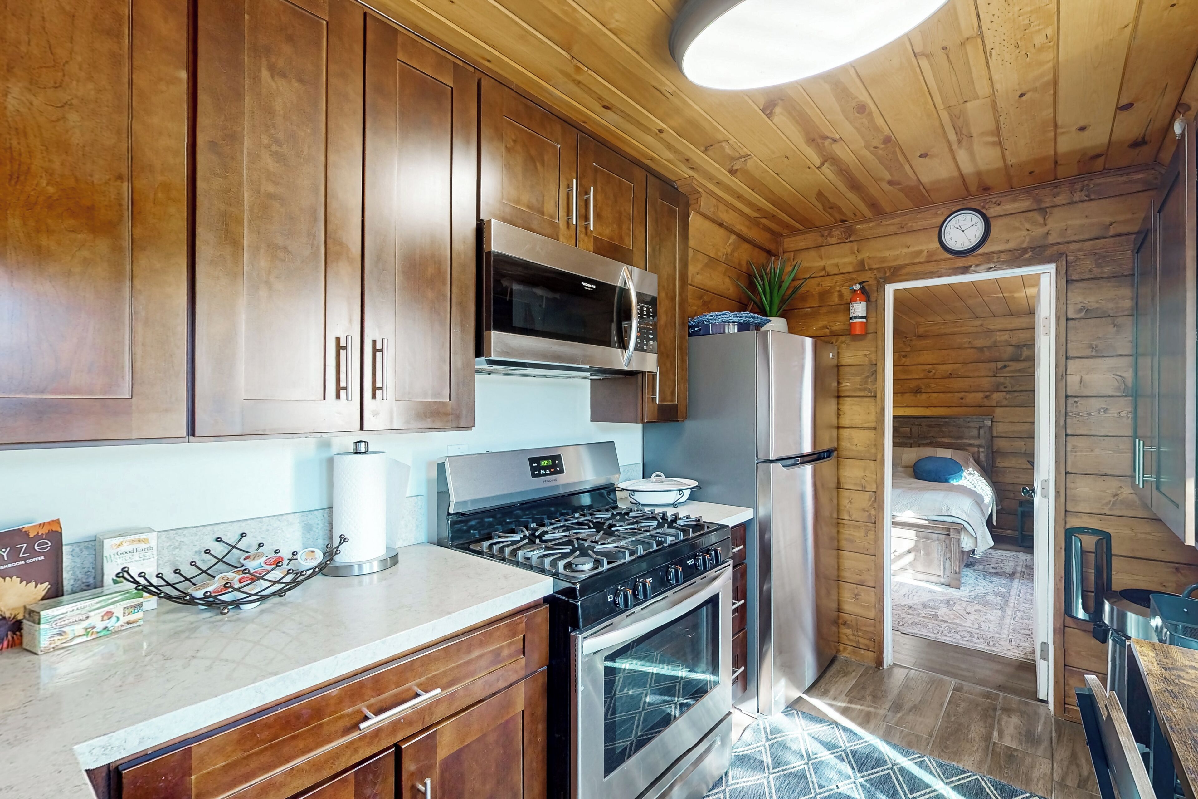 A compact kitchen with wooden cabinets, a stainless steel stove, and a microwave.