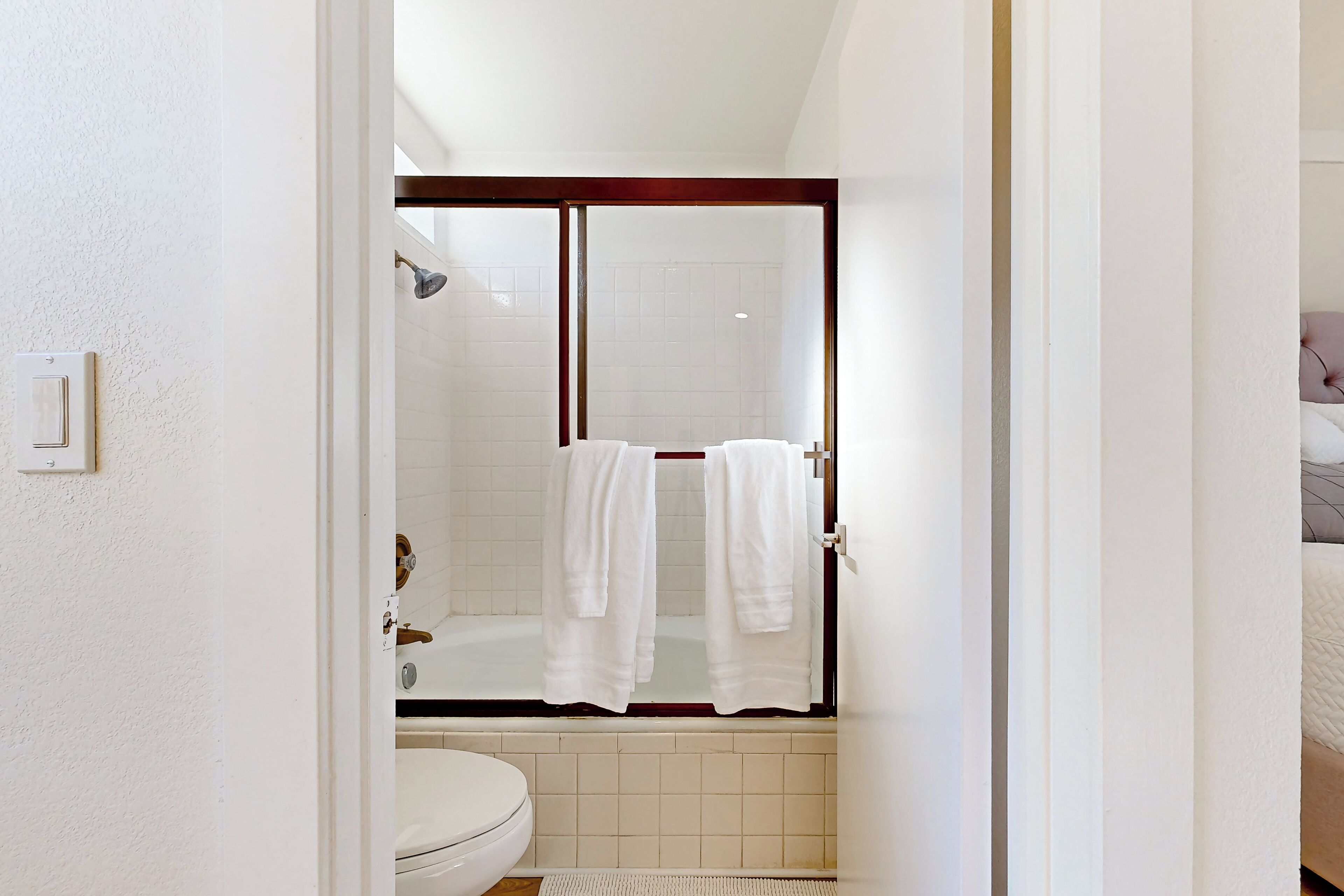A bathroom with a shower, toilet, and a towel rack with towels.