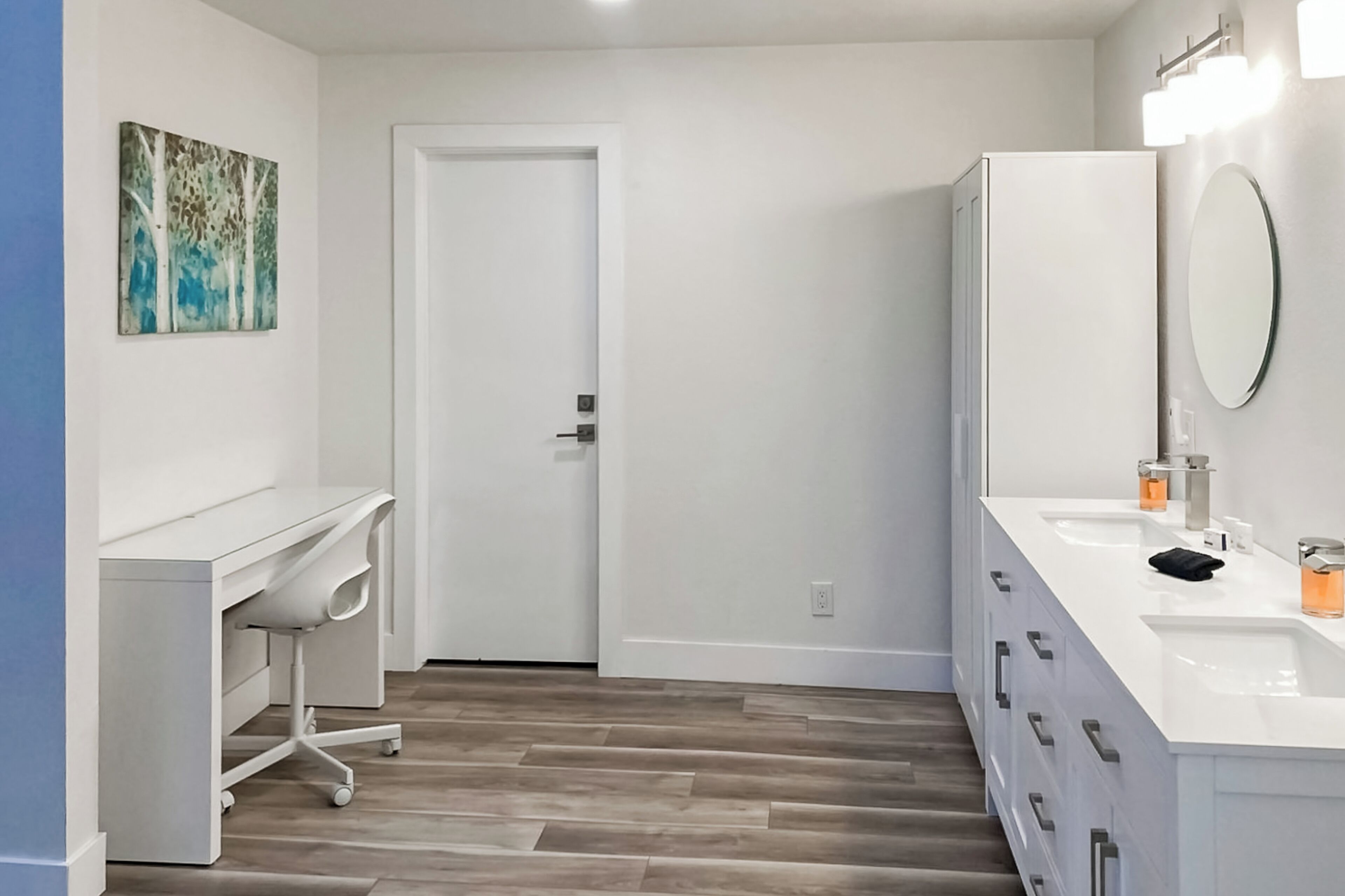 Une salle de bain moderne avec un meuble-lavabo blanc, un double évier et un grand miroir.