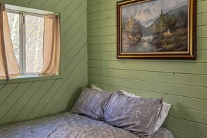 Une pièce avec un lit, une fenêtre avec des rideaux et un tableau encadré accroché au mur.