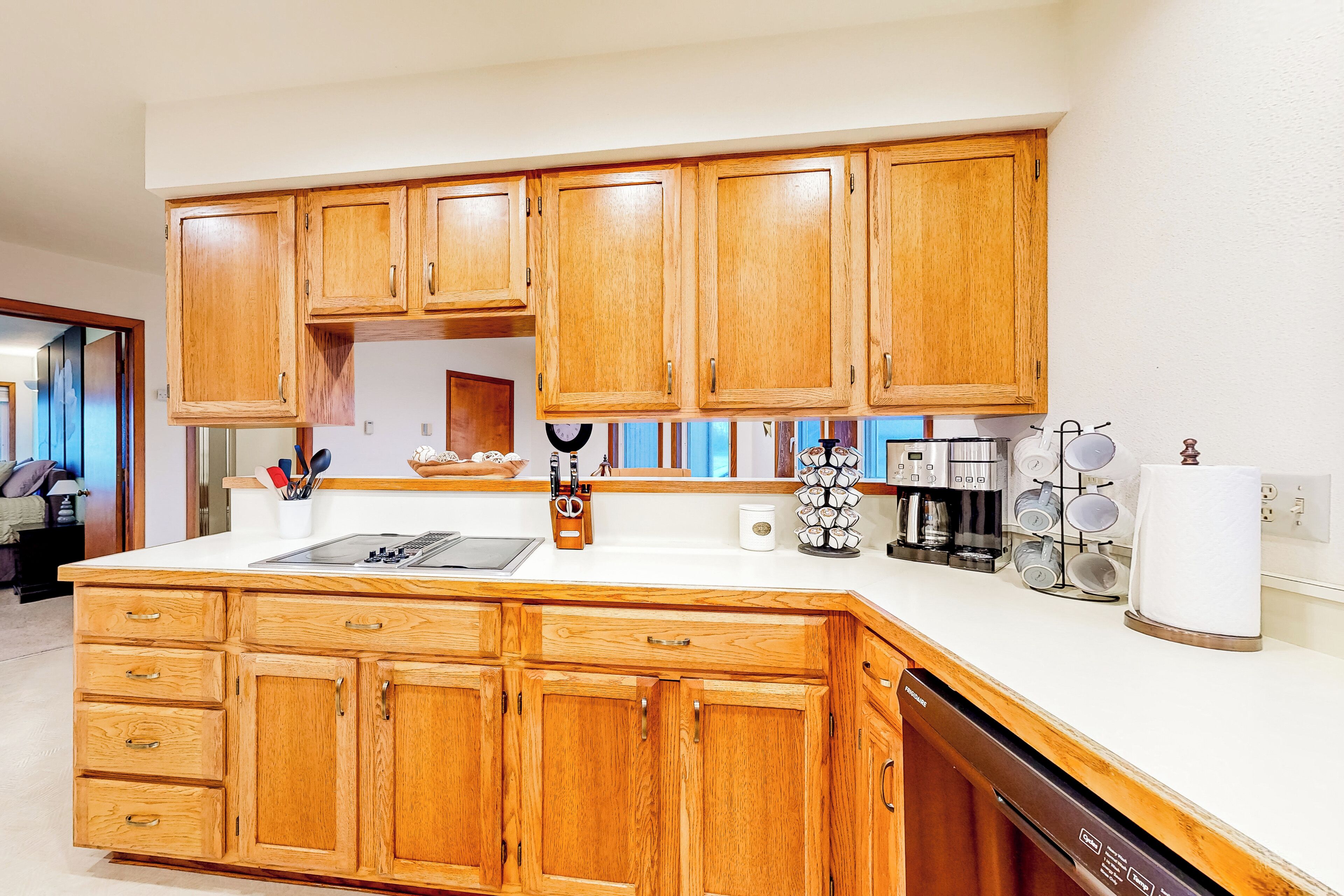 A kitchen with wooden cabinets, a white countertop, and a dishwasher.