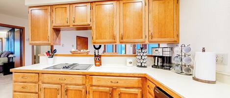 A kitchen with wooden cabinets, a white countertop, and a dishwasher.