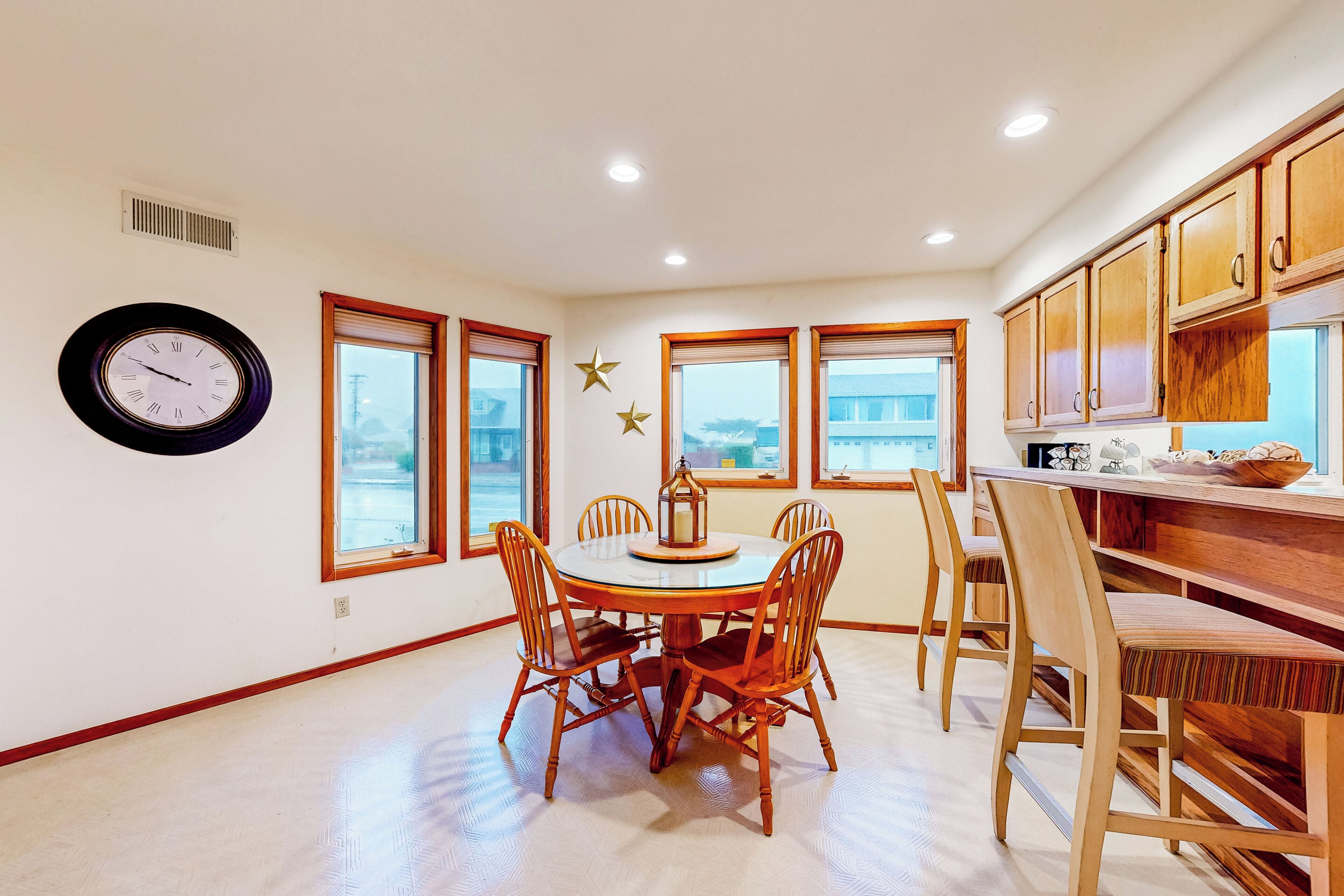 A dining area with a round table, wooden chairs, and a wall clock.