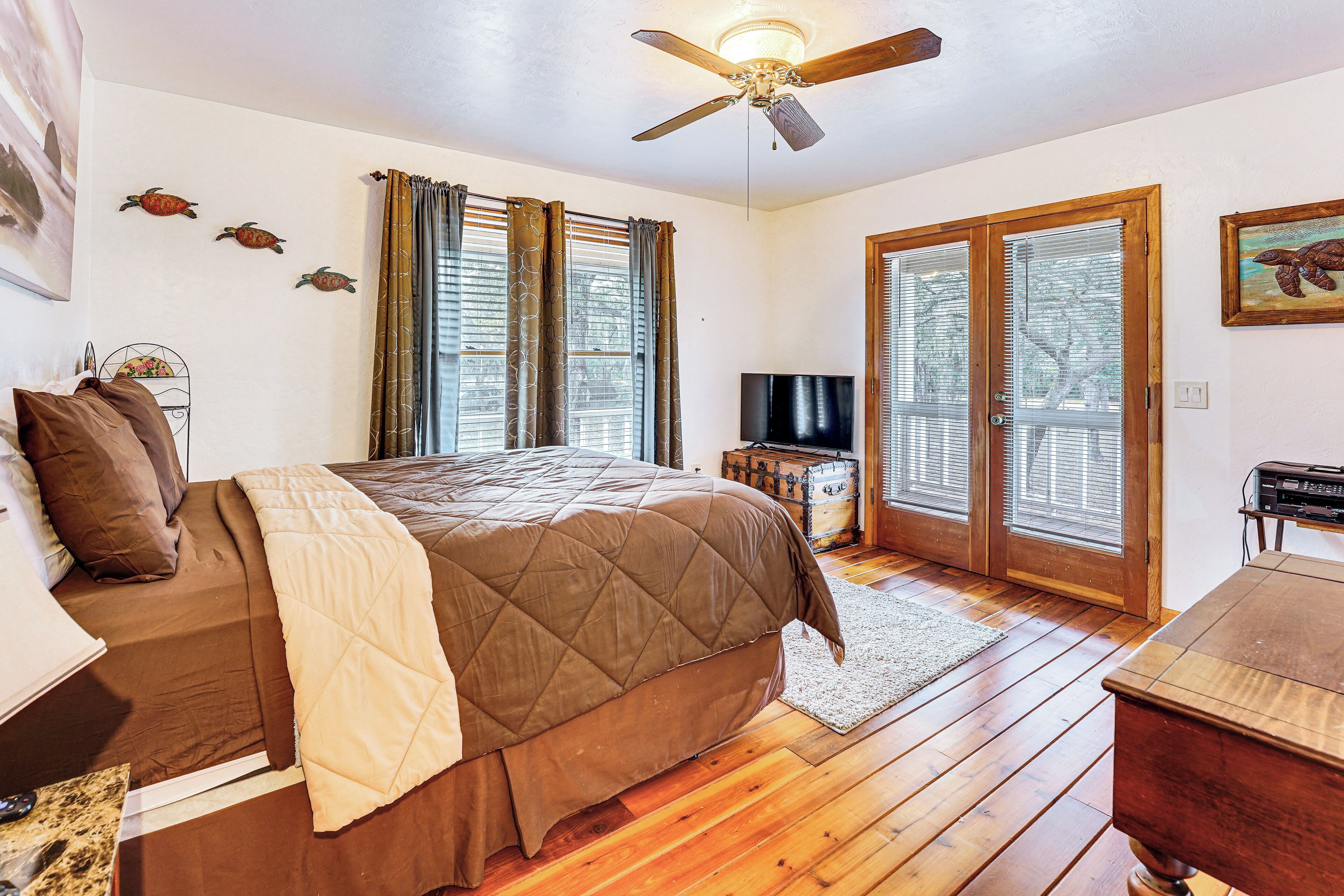 Ein Schlafzimmer mit Bett, Holzboden, Deckenventilator und Fernseher.