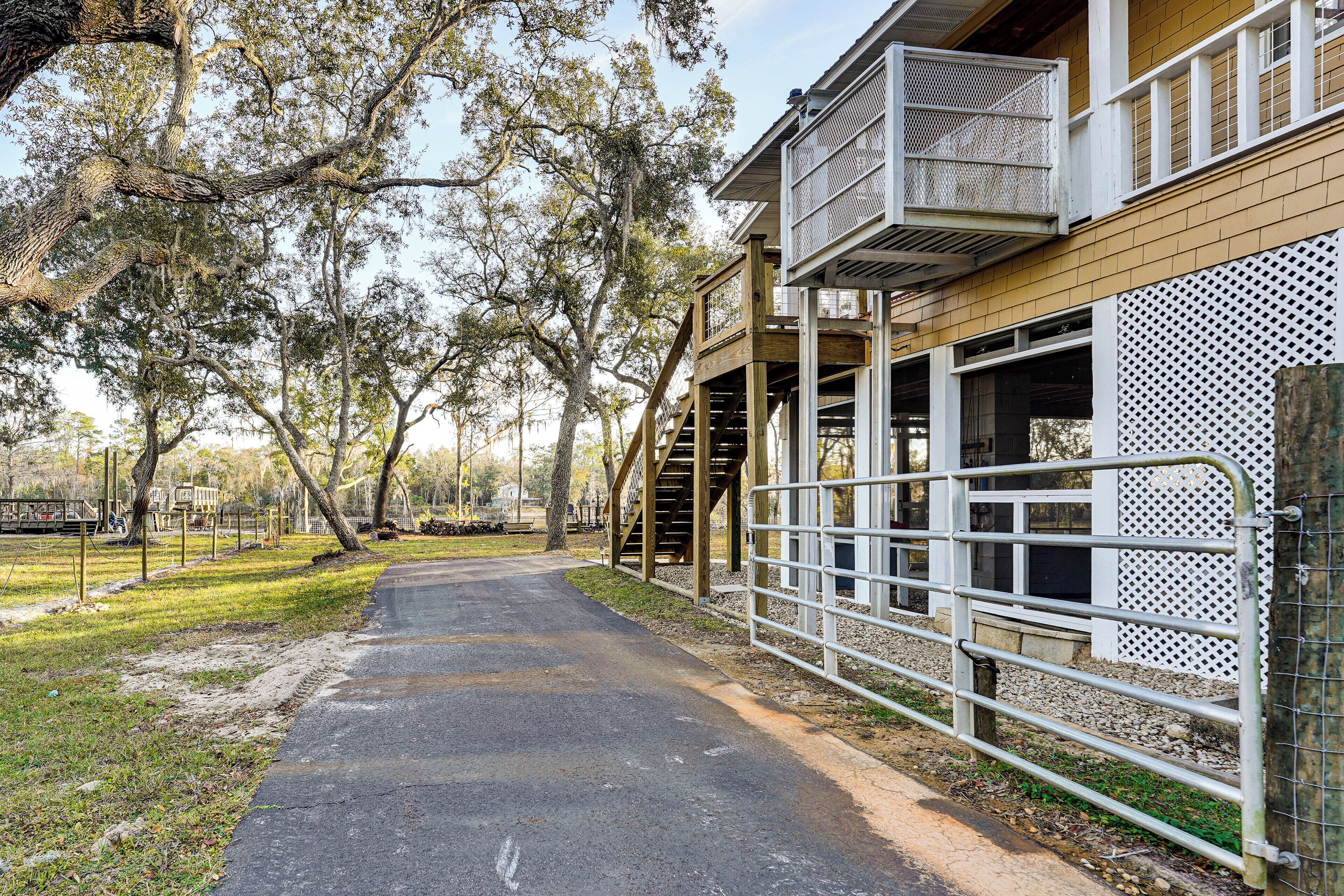 A pathway leading to a building with a covered area and a fenced enclosure.