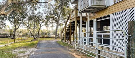 A pathway leading to a building with a covered area and a fenced enclosure.