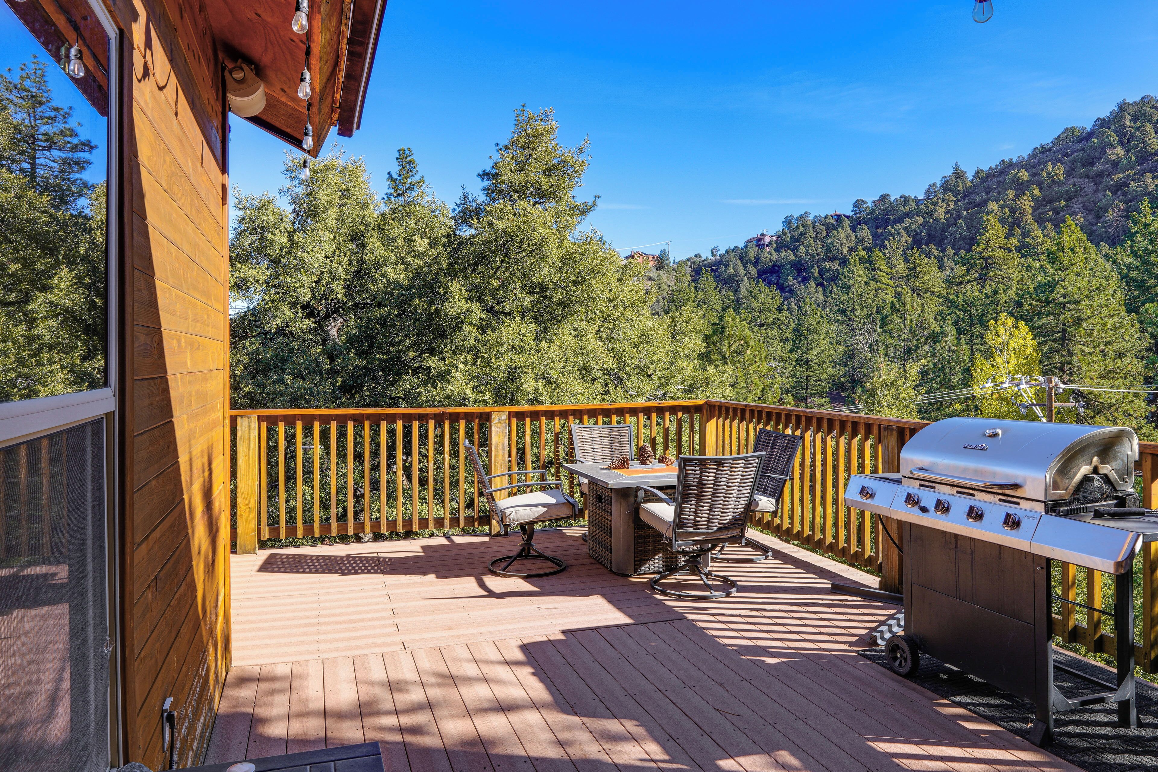 Una terraza de madera con una parrilla y mobiliario exterior.