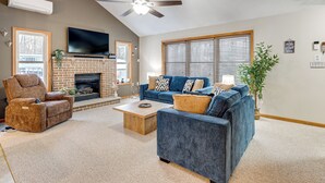 A living room with a fireplace, a blue sofa, a recliner, and a ceiling fan. - Arrowhead Lake Community Perks! Cozy Family Home (Pocono Lake)