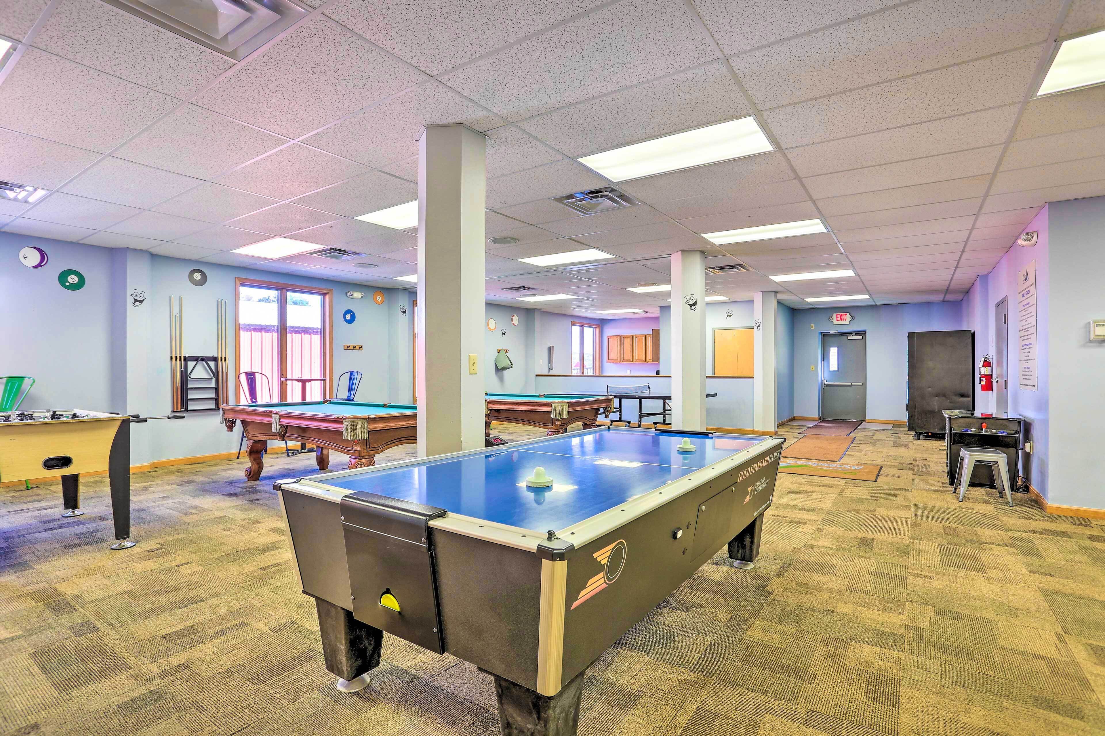 A pool table in a room with a carpeted floor, a window, and a door.